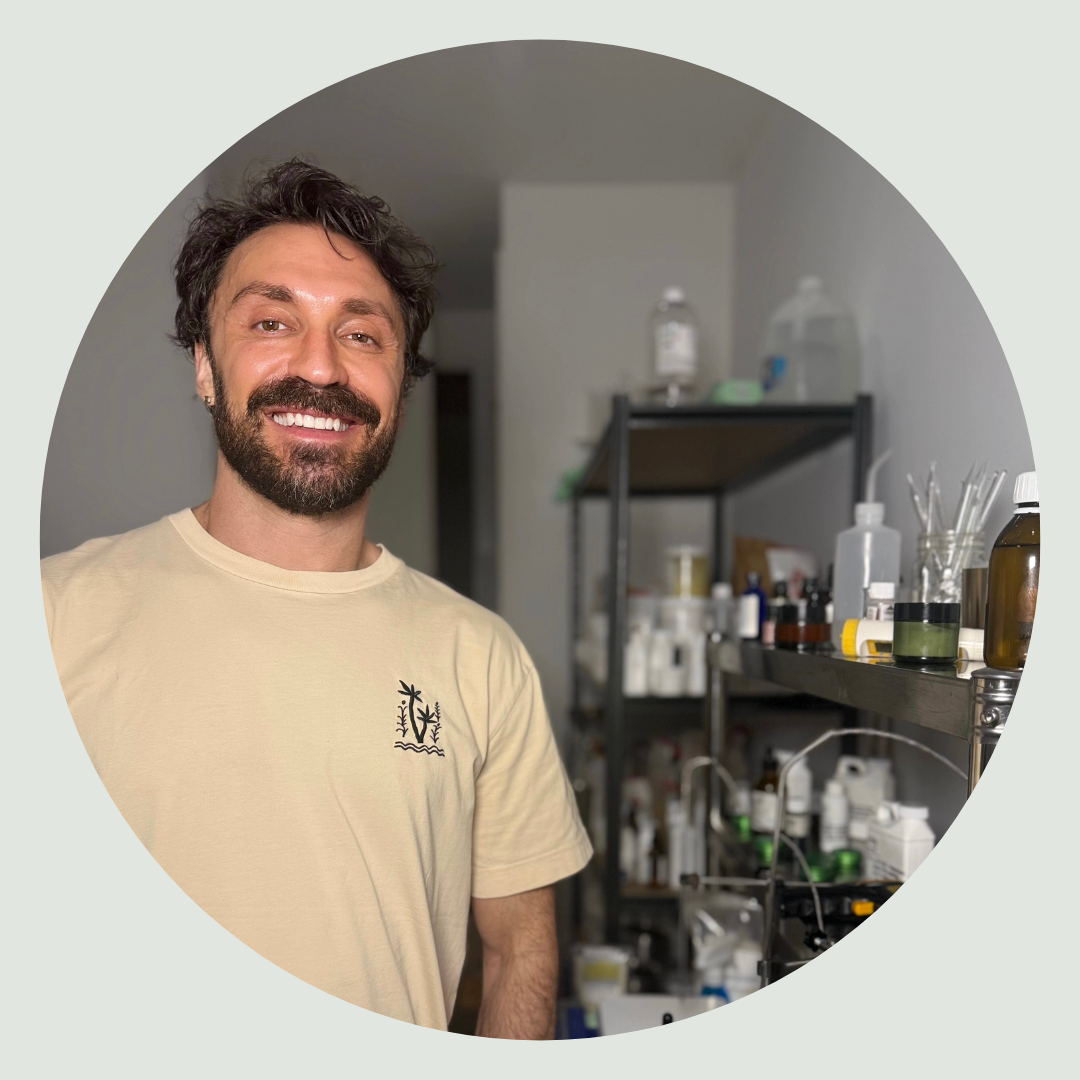 Meet Ish - founder of we are lab ish wearing a beige t-shirt with a logo in a laboratory setting